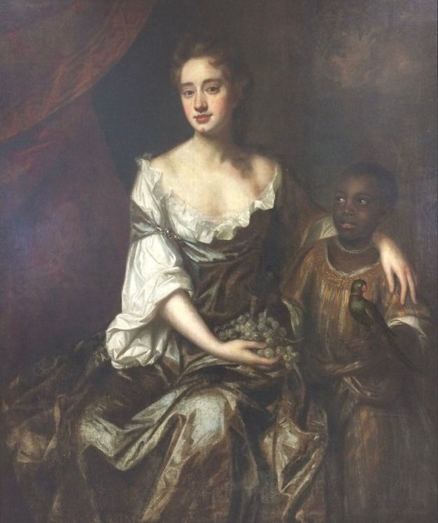 A baroque-style portrait depicting a seated woman in an elaborate dress with a ruffled neckline, holding a bunch of grapes. Beside her stands a young boy in ornate clothing, holding a small parrot. The painting exhibits rich, dark colors and intricate details, characteristic of the period. The woman gazes directly at the viewer, while the boy looks upward. The background is a deep, muted mix of brown and red tones, adding depth to the composition.